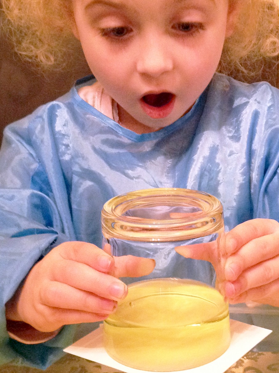 Amazed girl holding an inverted glass of coloured water